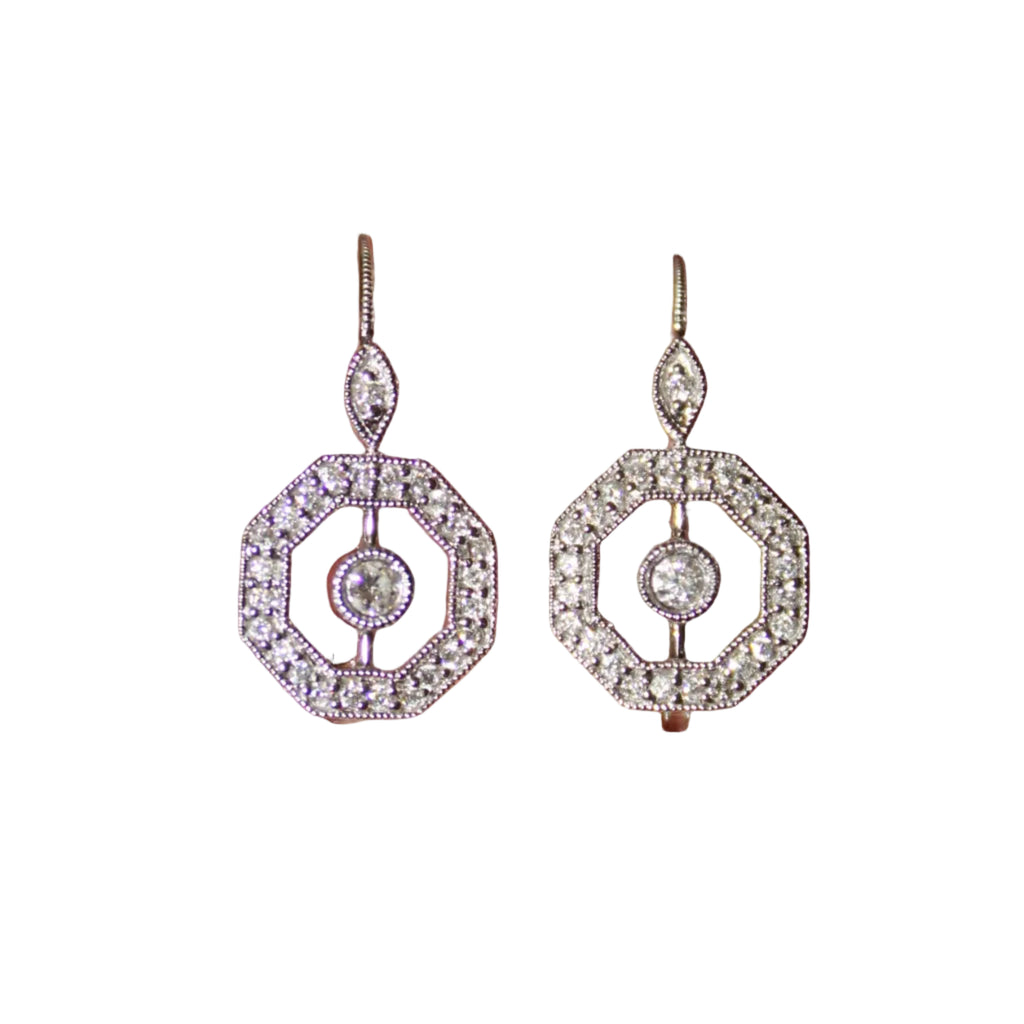 Pair of silver earrings held between two fingers against a blurred background