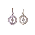 Pair of silver earrings held between two fingers against a blurred background