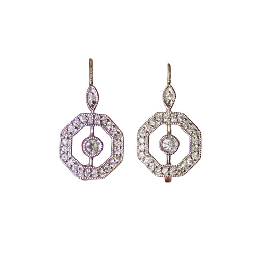 Pair of silver earrings held between two fingers against a blurred background