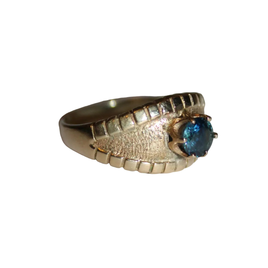 Gold ring with a blue gemstone on a light gray background