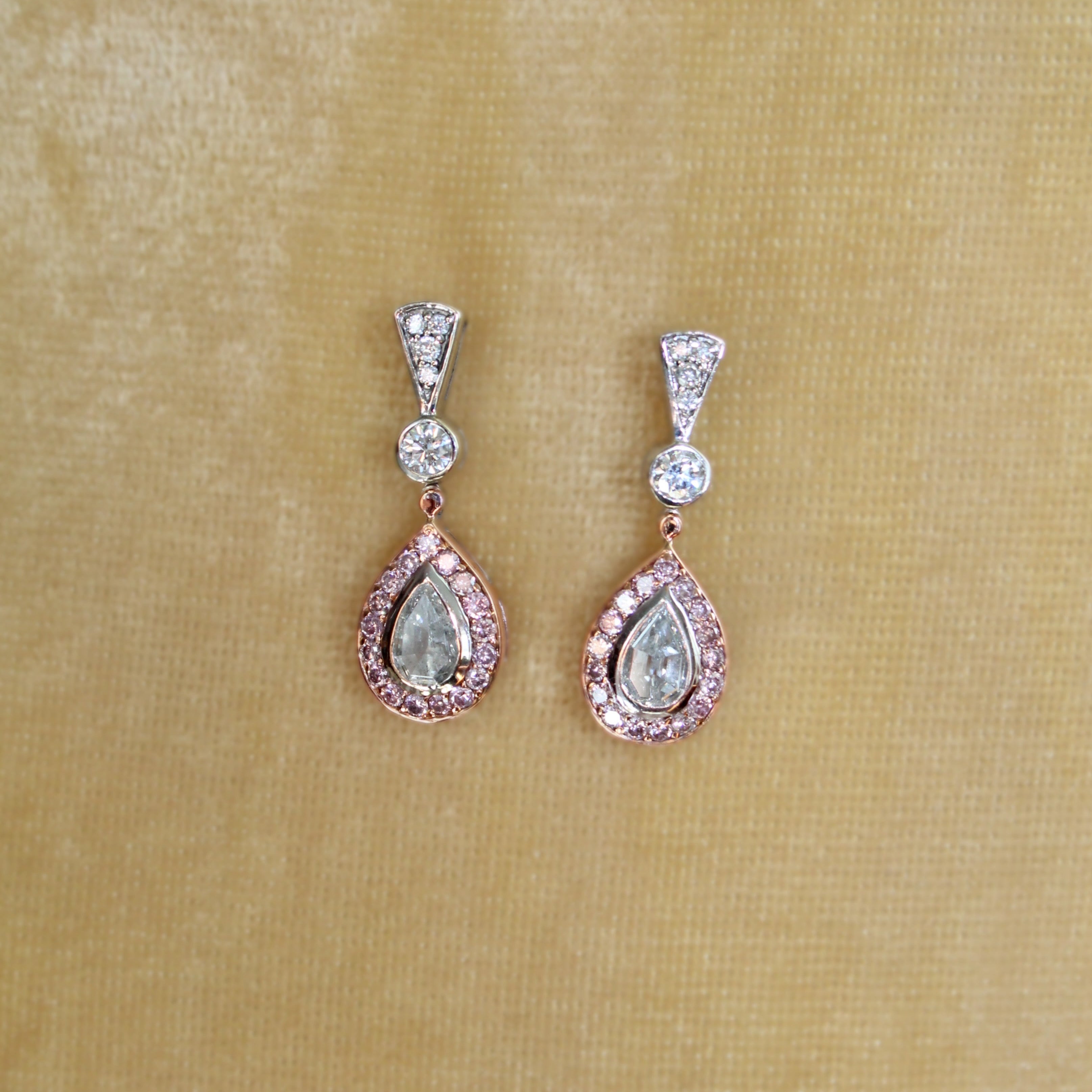 Teardrop-shaped earrings with gemstones on a beige fabric background