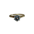 Gold ring with a blue gemstone on a white background