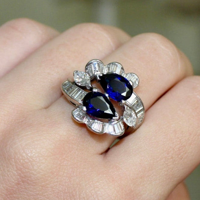 Silver ring with blue gemstones on a hand against a blurred background