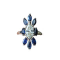 Ring with central diamond and blue gemstones on a white background