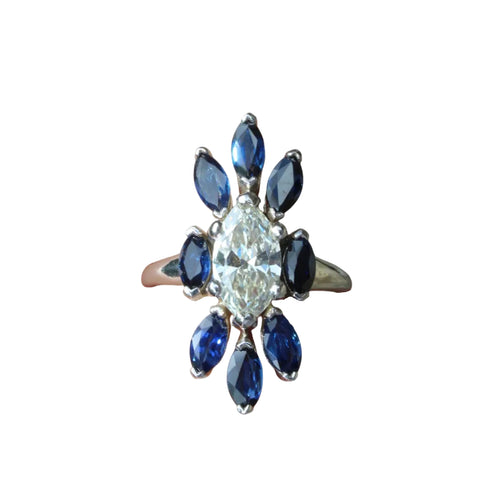 Ring with central diamond and blue gemstones on a white background