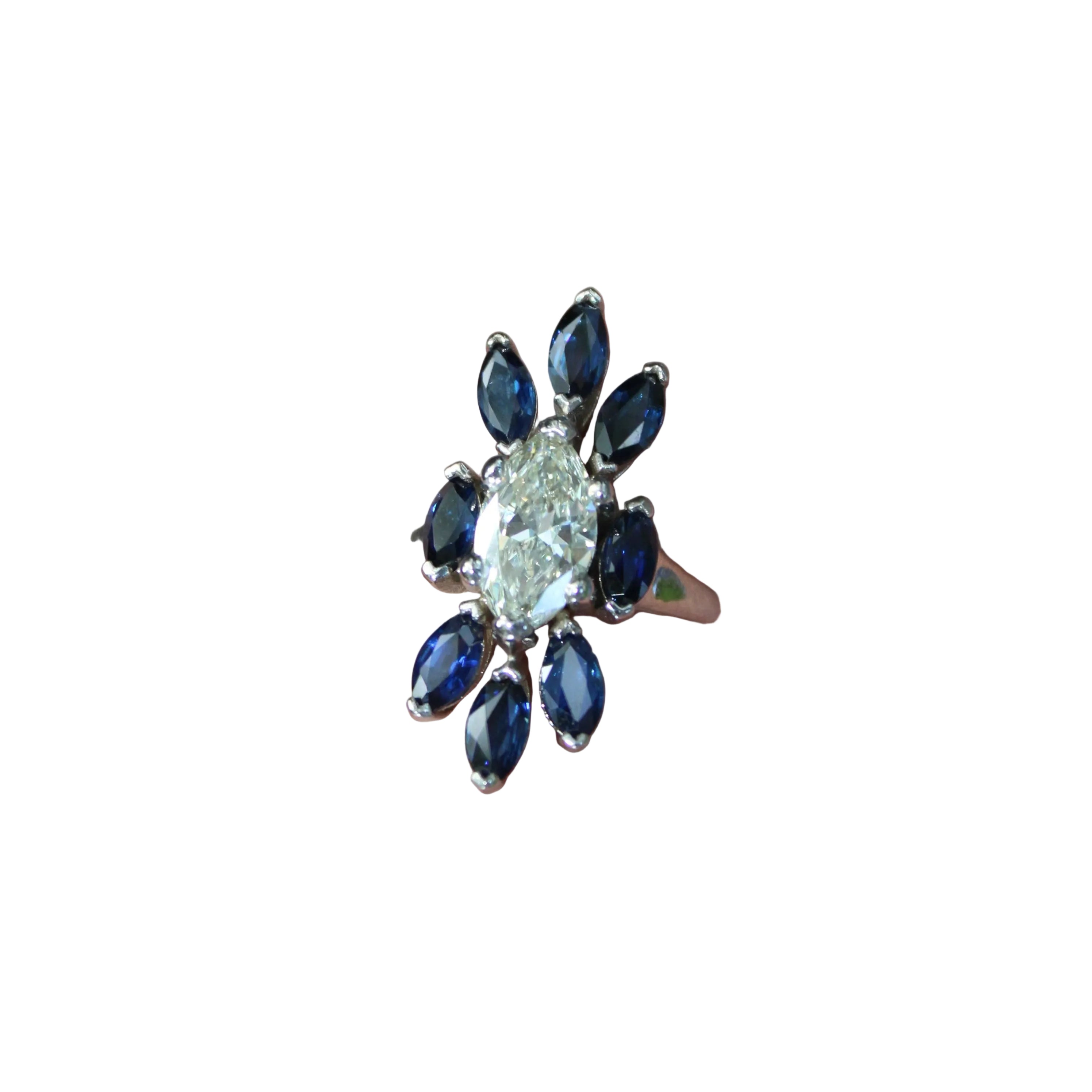 Ring with a central diamond and blue gemstones on a person's finger against a blurred background